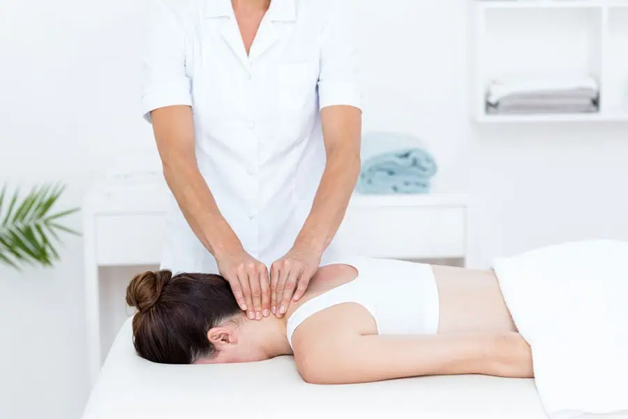 Medical massage therapist treating patient's neck for rehabilitation in Tampa clinic